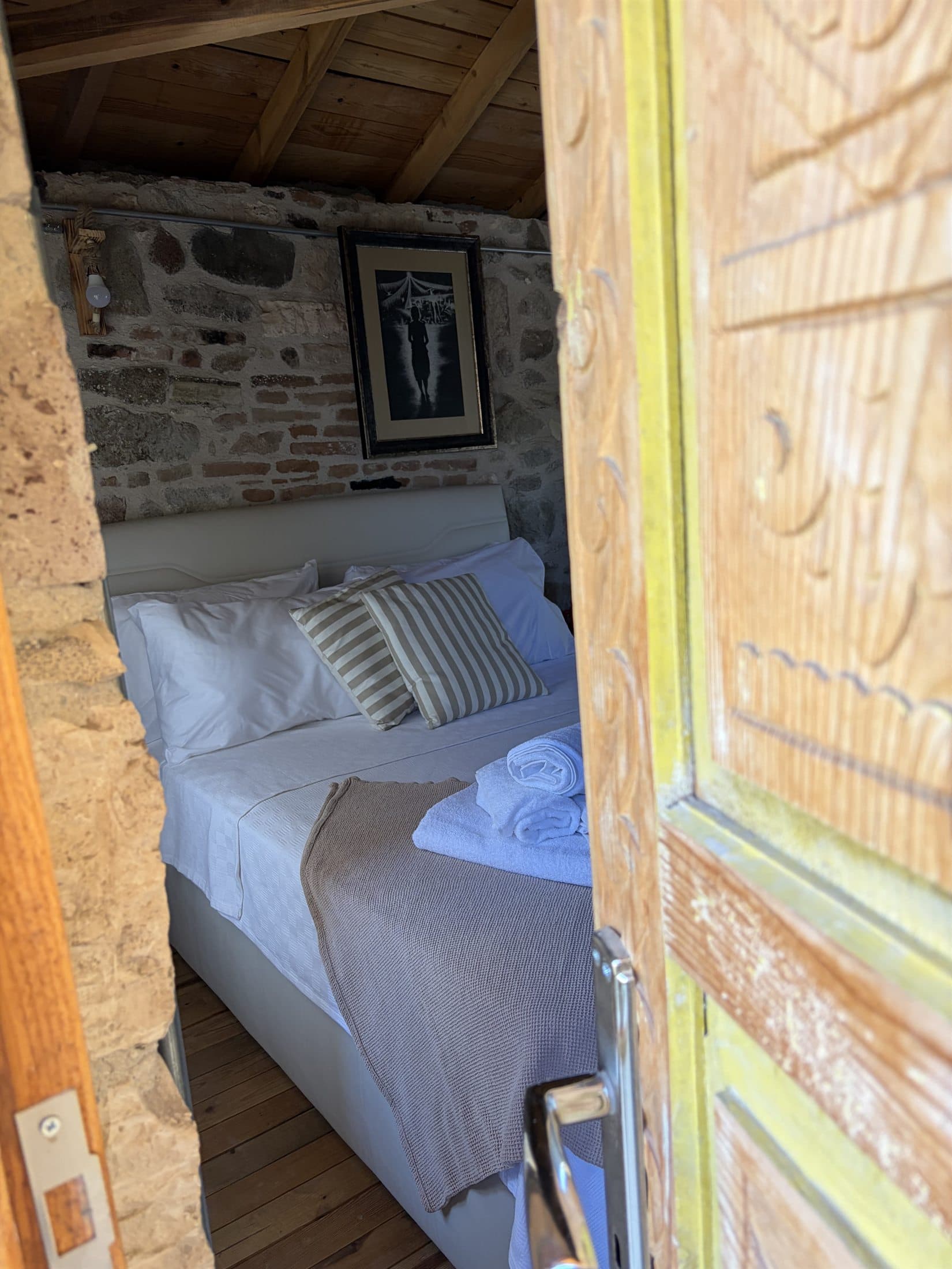 Vesta House Bademli'de taş duvarlı bir oda ve ahşap kapı