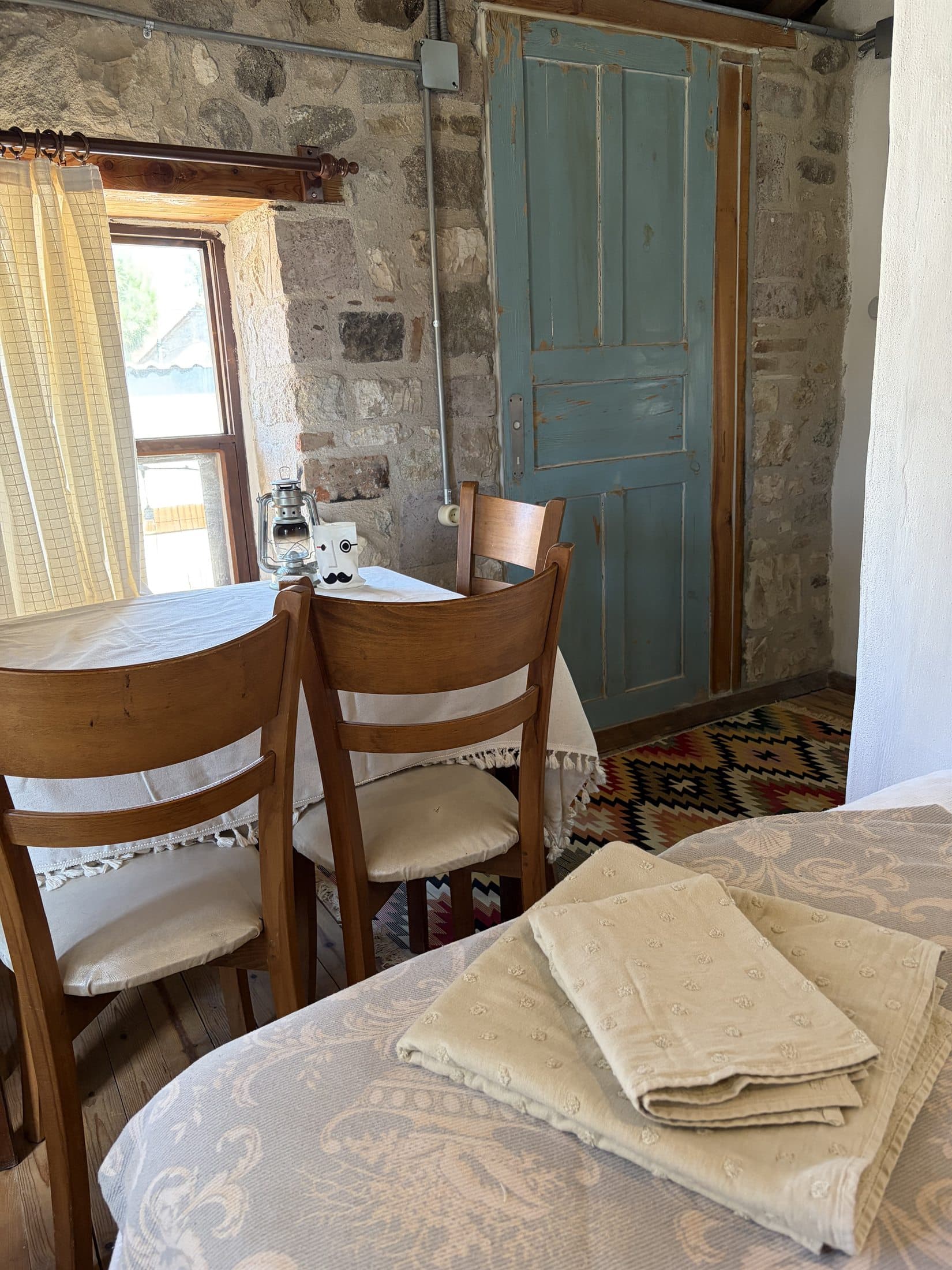 Vesta House Bademli'de kilim ve ahşap sandalyelerin bulunduğu bir oda köşesi